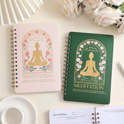 Two spiral-bound meditation notebooks, one pink and one green, on a light surface with flowers in the background, for mindfulness and mental health