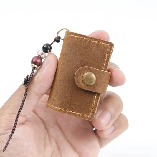 Brown leather keychain mini journal with beads held in a hand on a white background