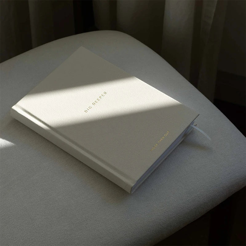 Dig deeper journal with gold text on a textured surface with sun rays -  for self-reflection, mindfulness, mental health support, and gratitude.